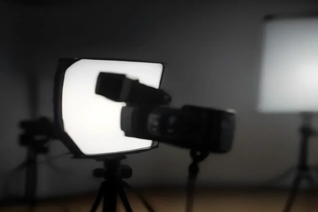 A professional broadcast camera on a tripod in a dimly lit studio
